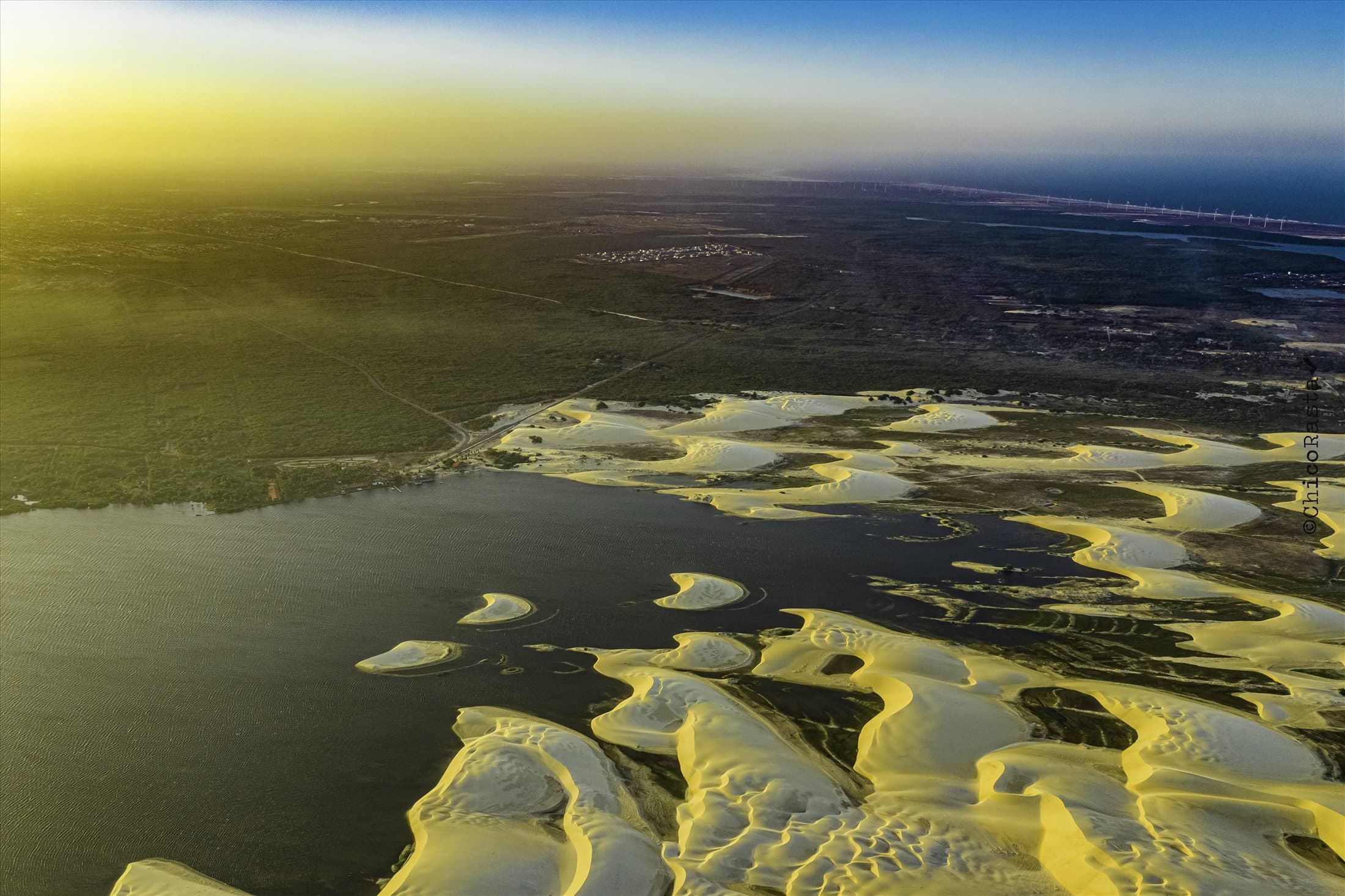 Paisagem aérea de dunas e litoral ao fundo